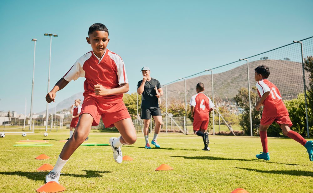 Latino boy in a red soccer uniform training on the soccer field Latino boy in a red soccer uniform training on the soccer field